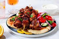 Souvlaki, a Greek dish, grilled meat shish kebab, on a plate with flatbreads, and lemon slices, grilled meat shish kebab, served with lavash, salad and drinks where there are no people [IBR125177933]
