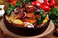 Ojakhuri, fried meat with potatoes, in ketsi, on a wooden table, Georgian cuisine, against a background of fresh ingredients [IBR125178021]