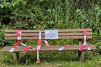 Blocked park bench with barrier tape and warning sign about oak procession spinners, Guxhagen, Hesse, Germany [IBR125180390]