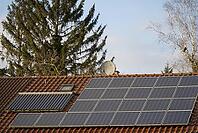 Residential house with solar thermal and solar panels on the roof. Behind the house there are tall conifers and a birch. A Blackbird Sits in the Thin Branches. The dream of living in the countryside [IBR125185833]