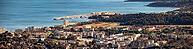 Broad view across the Bormes-les-Mimosas coastline with urban buildings, green hills and La Faviere marina under a clear sky, Bormes-les-Mimosas, La Faviere, Var, Provence-Alpes-Cote d Azur, France [IBR125185854]