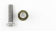New steel hex bolt beside cross-sectioned failed bolt showing corrosion pitting ring surrounding clean mechanical fracture center, stress-corrosion failure within 56 days of chlorinated chemical storage, industrial fire protection safety concept, white ba [IBR125200732]