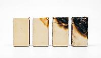 Four identical matchboxes in horizontal row showing progressive fire damage from pristine to heavily charred, same object four states, repeated industrial chemical incident and organizational learning failure concept, white background, studio shot, AI gen [IBR125200740]