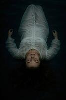Woman in a white dress floats peacefully on water at night, creating a mystical, calm scene, AI generated [IBR125203224]