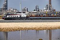 Rhine near Emmerich, extreme low water, Rhine level at 5 cm, downward trend, cargo ships sometimes have to travel with only 30 percent of the usual load, backdrop of the KLK Emmerich chemical plant, for oleochemical products, North Rhine-Westphalia, Germa [IBR113322387]