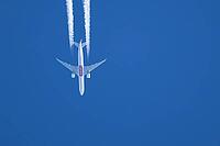 Boeing 777 jet passenger aircraft of Emirates airlines flying in a blue sky with contrails or vapour trails behind in the atmosphere, England, United Kingdom [IBR125204145]