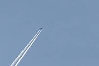 Jet passenger aircraft flying in a blue sky with contrails or vapour trails behind in the atmosphere, England, United Kingdom [IBR125204182]