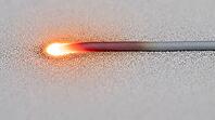 Laser weld line trailing across a titanium powder bed, cooling from white-hot to matte grey, laser powder bed fusion process, studio shot, AI generated [IBR125211520]
