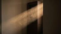 Sunbeam cutting through a dim living room revealing suspended particulate haze, indoor wildfire smoke contamination concept, AI generated [IBR125211541]