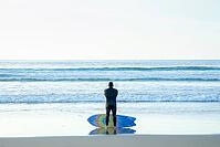 A male surfer contemplating the ocean in La Jolla, California [IBR125242394]