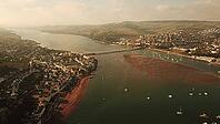 Aerial view of a river estuary, village, and surrounding green hills with bridges and boats, Teignmouth, Devon, UK [IBR125242397]