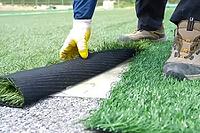Spreading artificial turf in the stadium, rolling out rolls of lawn and leveling [IBR125242408]