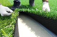 Spreading artificial turf in the stadium, rolling out rolls of lawn and leveling [IBR125242427]