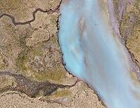 An aerial view of a glacial river braiding across Iceland's volcanic sandur plain, its milky turquoise water fed by meltwater from a nearby glacier, Iceland [IBR125242445]