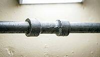 Extreme macro of a pipe support bracket with a barely perceptible gap from its mounting mark, evidence of water hammer vibration damage, studio shot, AI generated [IBR125242471]