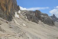 Hiking on a rocky mountain trail with boulders and peaks under a blue sky [IBR125261554]