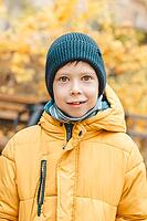 Portrait of a smiling boy in a hat and a yellow jacket, On the street. Walk in the street in autumn. Handsome and cute boy smiling looking into the frame [IBR125261560]