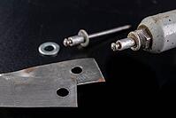 Riveting two pieces of metal sheet. Connecting steel with rivets. Dark background [IBR125261631]