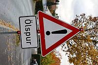 Danger from oil slick: warning sign on the side of the road [IBR125280358]