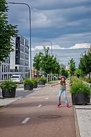 Child practicing inline skating on a designated metropolitan track surrounded by green trees and contemporary architecture representing outdoor fitness and summer sports [IBR125280376]
