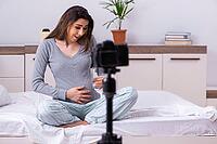 The pregnant woman is recording video for her blog [IBR125304626]