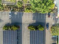 Aerial view of solar panels installed as shade roof over parking lot for parked cars. Photovoltaic technology integrated in urban infrastructure. [IBR125324055]