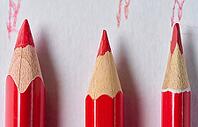 A row of wooden red pencils with sharp tips for drawing on a white background [IBR125331121]