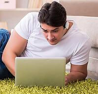 The man working on a laptop on the carpet at home [IBR125331123]