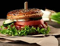 Cheeseburger with minced meat, green lettuce and ketchup on a wooden brown kitchen board, close up [IBR125331179]