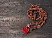 Rudraksha prayer beads for meditation on a brown wooden background, top view. Japa mala, copy space [IBR125331199]