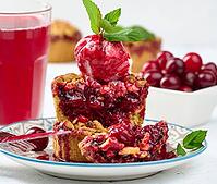 Cherry crumble pie decorated with a scoop of ice cream and drizzled with cherry sauce on a plate, white [IBR125331210]