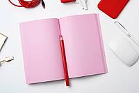 Open pink paper notebook, power bank with cable, red smartphone, headphones, wireless mouse on white background, workplace, top view, flat lay [IBR125344234]