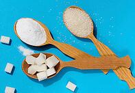 Wooden spoons with different types of white sugar powder, granulated sugar and cubes on blue background, top view [IBR125344236]