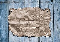 Brown kraft paper with burnt edges on an old cracked wall [IBR125344248]