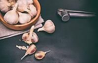Fruit of garlic in a wooden bowl and on a table, black wooden background [IBR125344251]