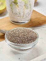 Clear glass bowl filled with dry chia seeds, top view [IBR125344260]