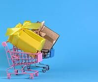 Yellow gift box with a silk bow in a miniature metal trolley on a light blue background. Party Backdrop, Surprise, Seasonal Sale [IBR125344302]