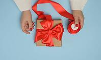 Two female hands holding gift boxes tied with a red ribbon on a blue background. Top view [IBR125344304]