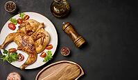 Whole fried chicken with spices in a white round plate on the table, top view. Copy space [IBR125344305]