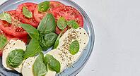 Classic Caprese salad with sliced ??fresh tomatoes, mozzarella and basil leaves on a blue plate, top view. Copy space [IBR125344306]