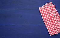 Folded red and white cotton kitchen napkin on a wooden blue background, top view, copy space [IBR125363547]