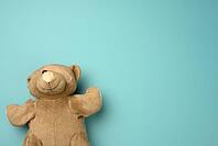Old teddy bear with a band-aid on the eye lies on a blue background, top view, copy space [IBR125363568]