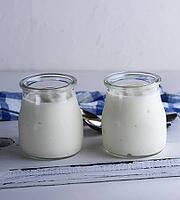 Homemade yogurt in a glass jar on a white wooden board, close up [IBR125363584]