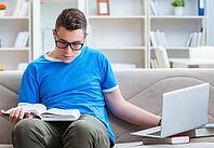 The young student is preparing for exams and studying on a sofa at home [IBR125382586]