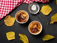 Cottage cheese dessert baked in portioned round ceramic plates on a wooden black table, top view [IBR125382600]