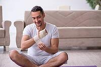 The hand-injured man is doing exercises at home [IBR125382605]