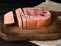 Sliced boiled sausage with slices of whole meat on a brown wooden cutting board, close up [IBR125382612]