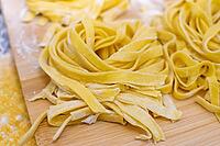 Close up of hands making home made italian pasta with flour, eggs and pasta machine [IBR125382613]