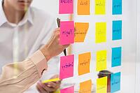 Business people planning startup project placing sticky notes session to share idea on glass wall, Strategy Analysis Office Concept [IBR125382619]