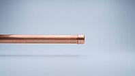 A capped copper pipe section with a smooth metal end cap and even exterior surface, no visible marks or moisture, on a plain grey studio background, close-up product shot, AI generated [IBR125395944]